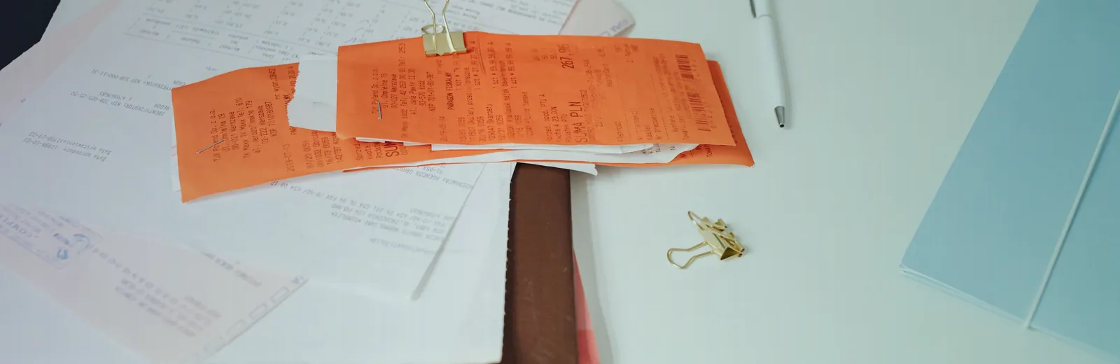 Stack of receipts, invoices and stationery being organized on a desk