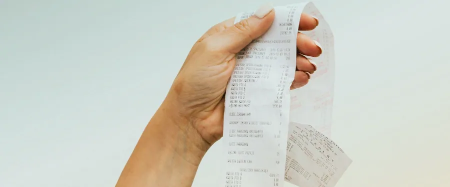 Hands holding a long paper receipt before scanning it into ReceiptLah